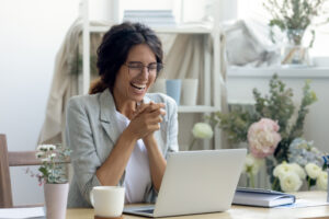 laughing female enterpreneur decorator reading good news on laptop screen