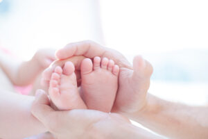father cradling baby boy's feet